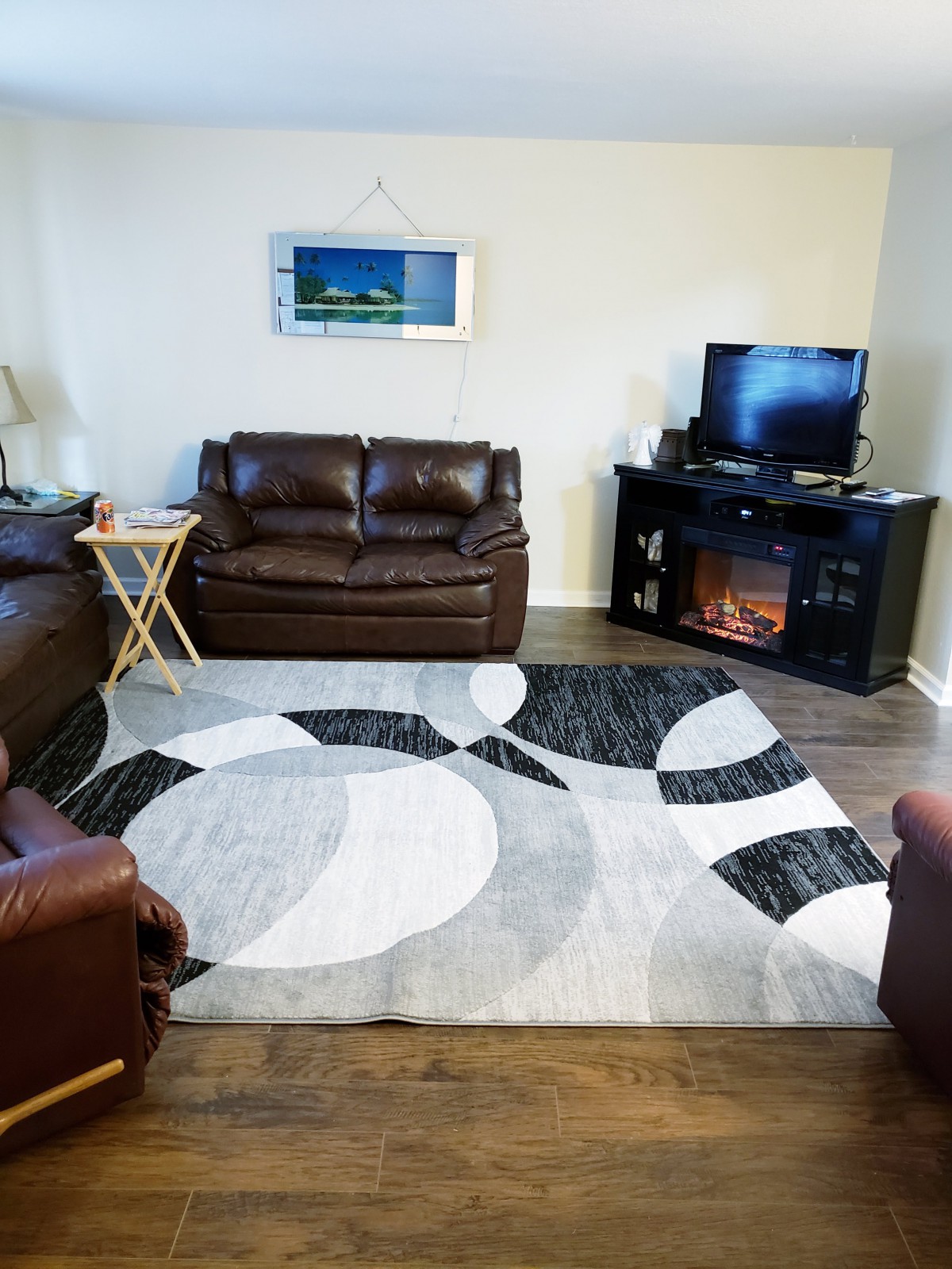 A cozy living room with a modern rug, leather sofas, and a television.