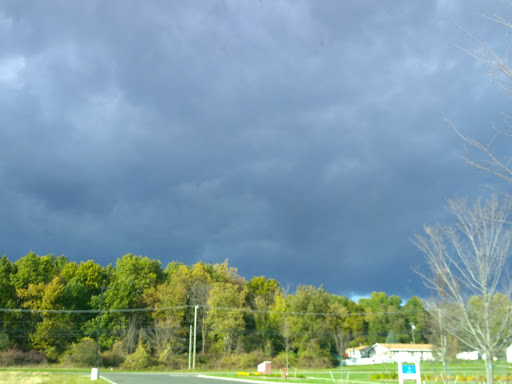 A dark and ominous sky signals an approaching storm over a green landscape.