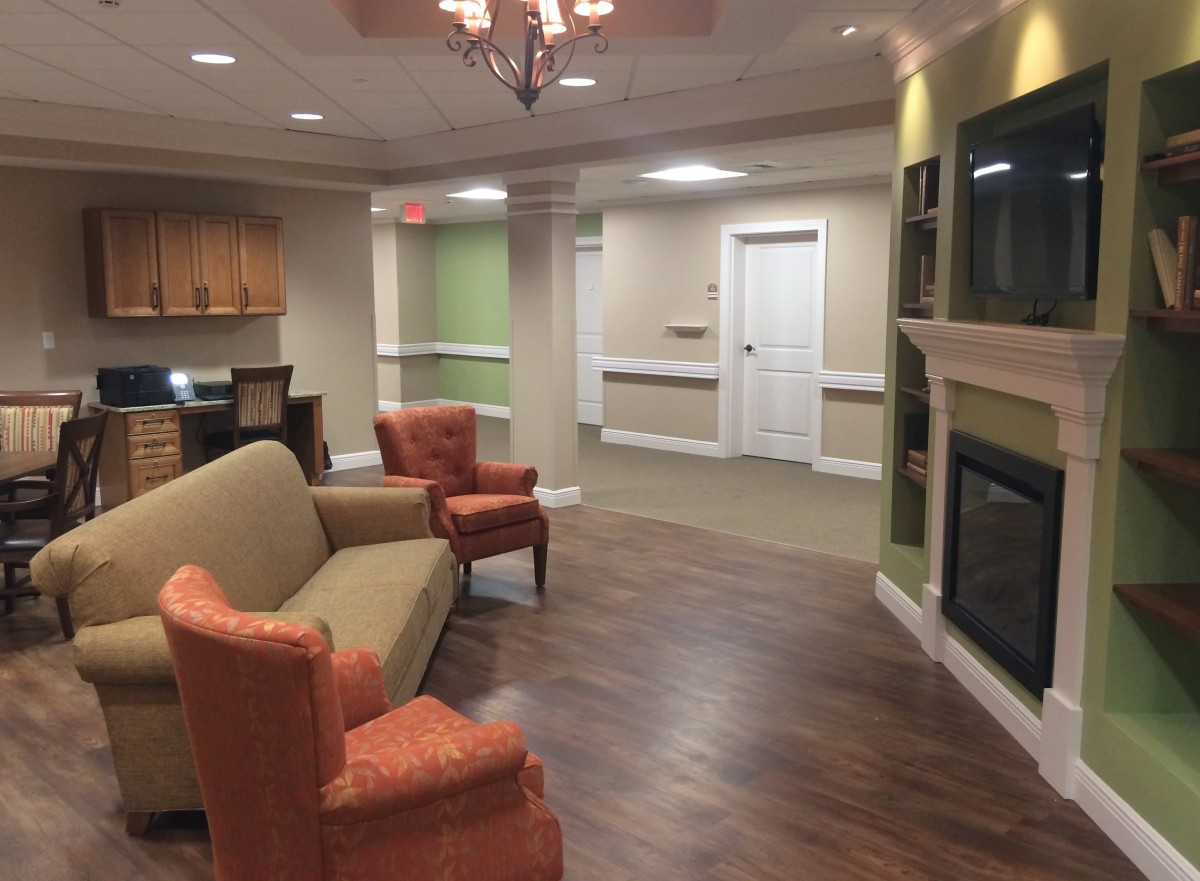 A cozy lounge area featuring a sofa, chairs, and a fireplace with hardwood flooring.