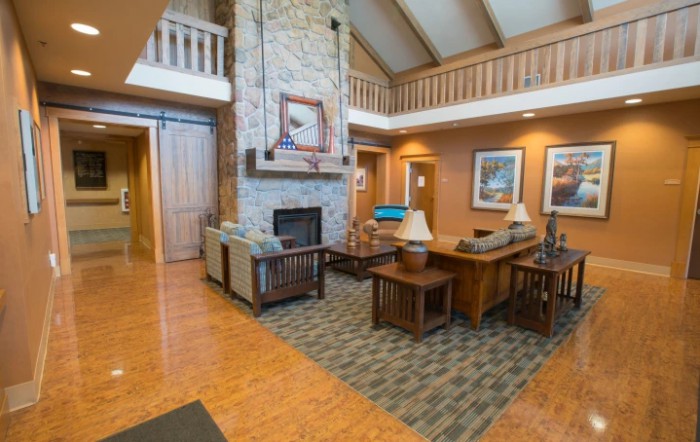 A cozy living room with a stone fireplace, wooden floor, and comfortable furniture.