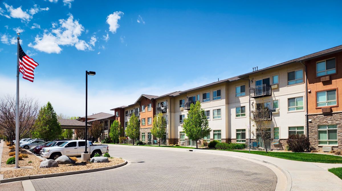 A modern apartment building in a suburban residential area on a sunny day.