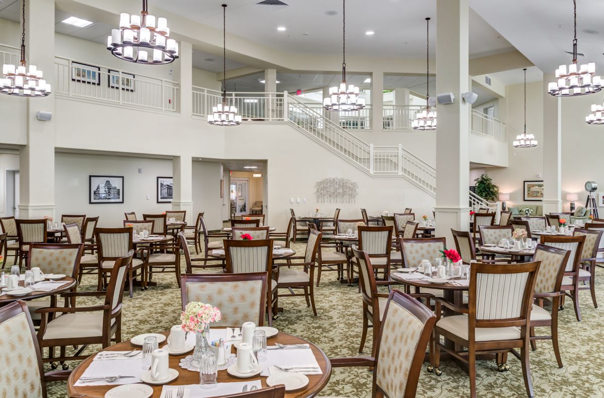 A spacious and elegant dining area with neatly arranged tables and chairs, illuminated by chandeliers.