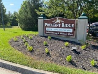 Entrance sign for Pheasant Ridge Assisted Living & Memory Care surrounded by landscaping.