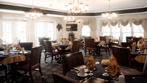 An elegant dining room with neatly arranged tables and chandeliers.