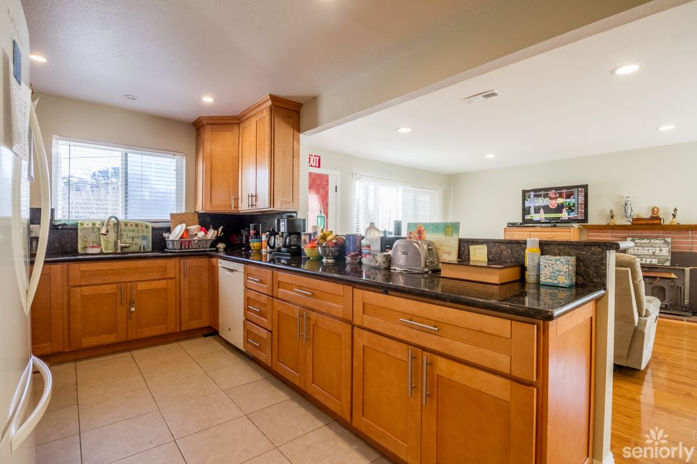 A spacious kitchen with wooden cabinets and a black countertop, featuring modern appliances.