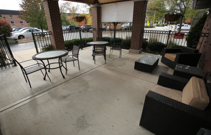 An outdoor patio with tables and chairs under a covered area.