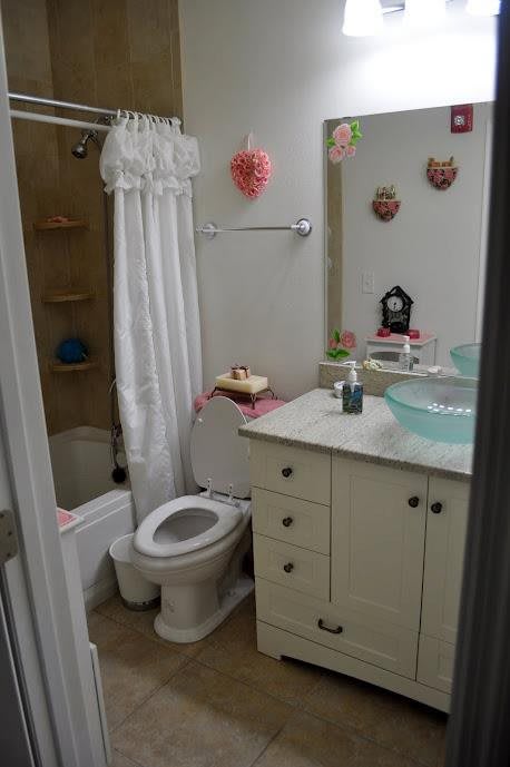 A small, decorated bathroom with a white shower curtain and vanity.