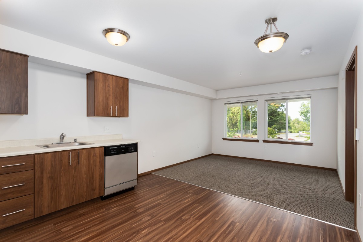 A modern open-concept kitchen and living area with hardwood floors and large windows.