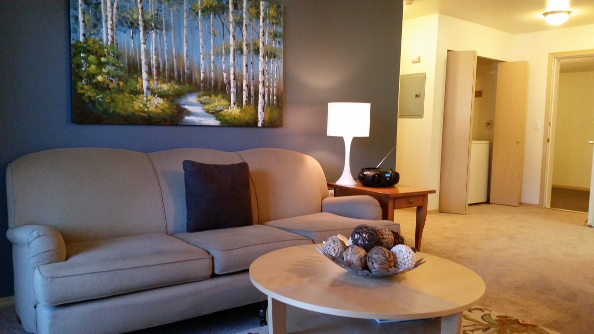 A cozy living room with modern decor, featuring a sofa, artwork, and a stylish lamp.