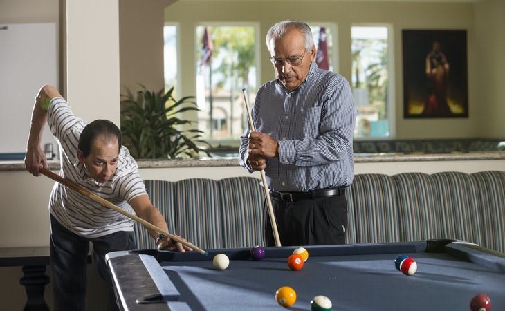Two people playing billiards indoors.