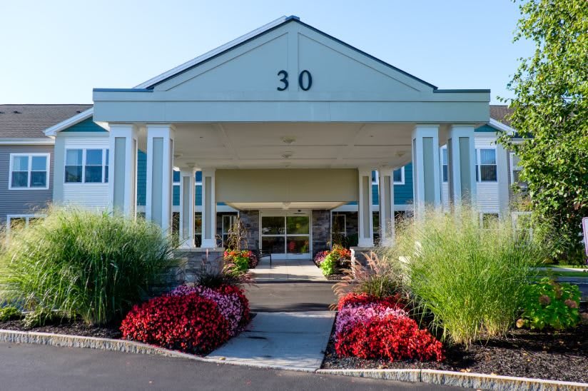 A building entrance with well-maintained landscaping and colorful flowers.