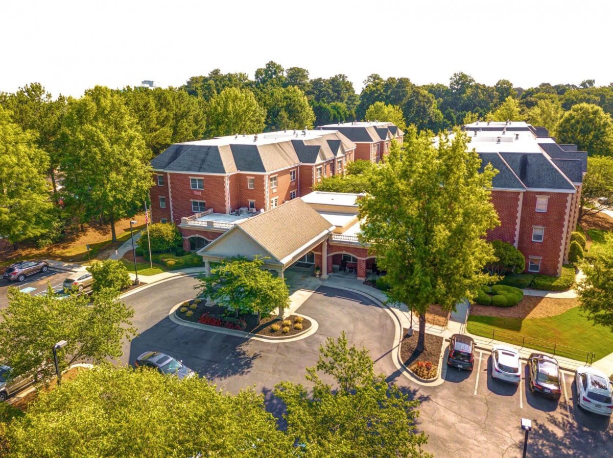 An aerial view of a brick building surrounded by trees and a parking lot.