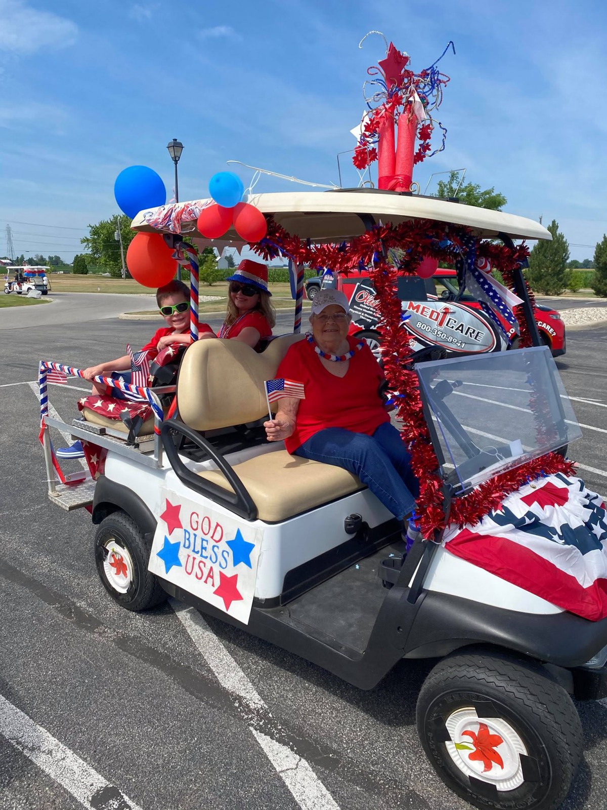 A festive golf cart decorated in red, white, and blue with balloons, ready for a parade.