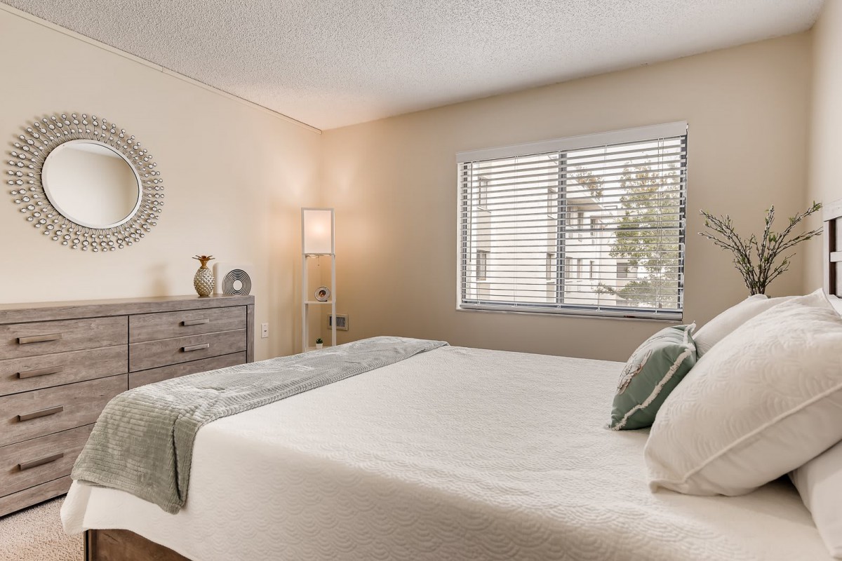 A minimalist and modern bedroom with a neatly made bed, dresser, and decorative items.