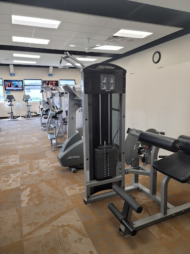 A well-equipped gym featuring various exercise machines, including a cable machine and weight benches.