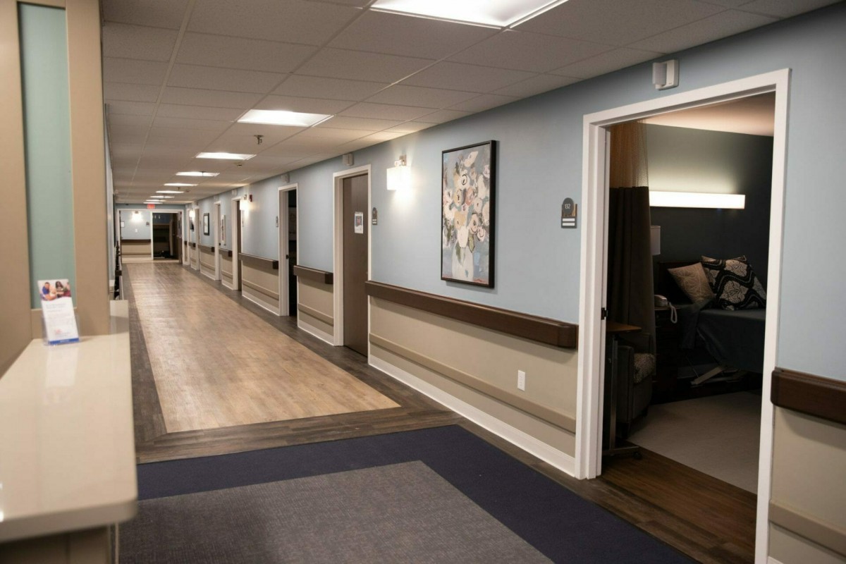 A well-lit hallway with multiple doors and framed artwork on the walls.