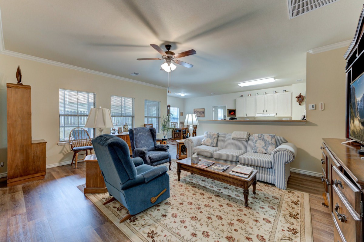 A cozy living room with a sofa, armchairs, and a coffee table under a ceiling fan.