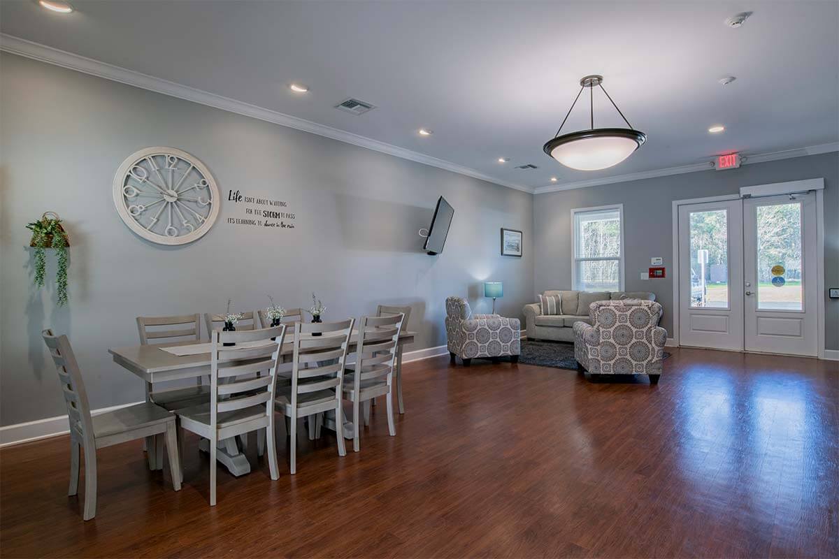A cozy living and dining area with hardwood flooring, stylish furniture, and a modern chandelier.