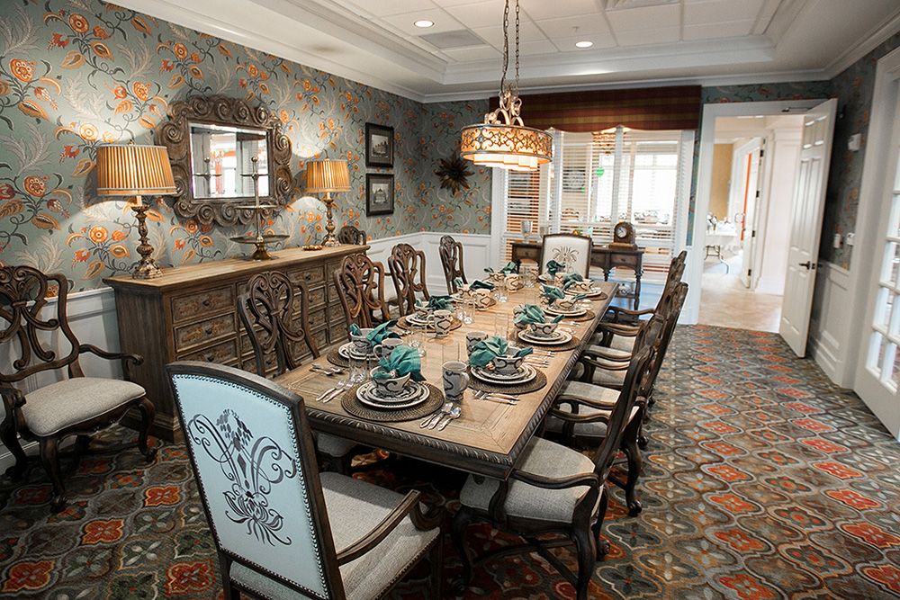 An elegantly decorated dining room featuring a long wooden table, ornate chairs, and a chandelier.