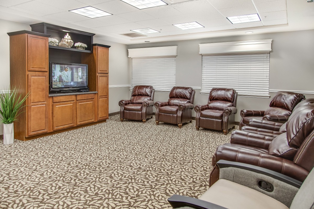 A cozy waiting room with leather recliner chairs facing a television.