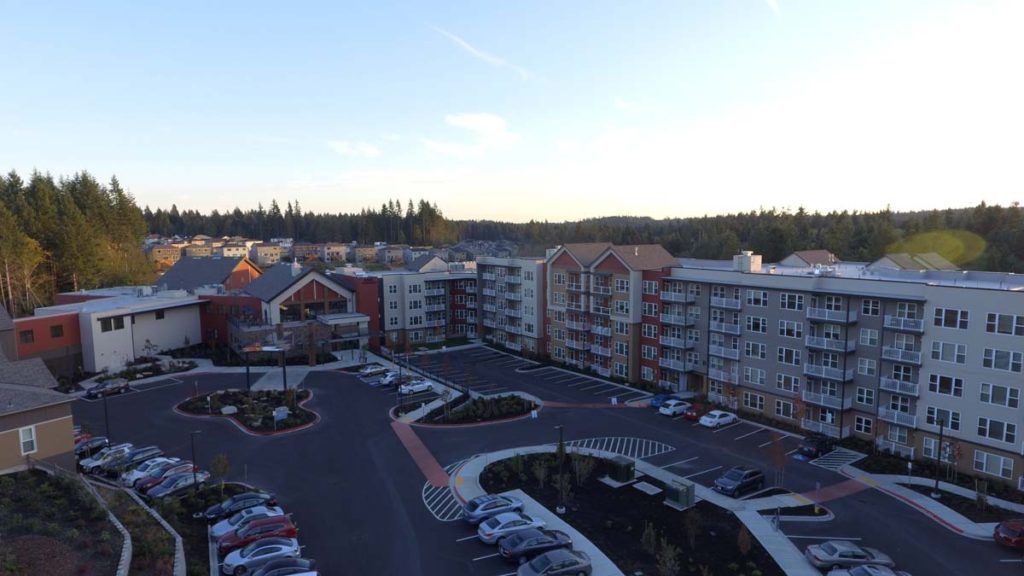 A view of a residential apartment complex with a parking lot at dusk.
