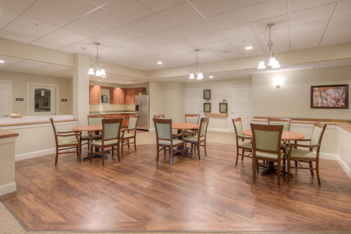 A spacious dining area with wooden flooring, elegant tables and chairs, and ambient lighting.