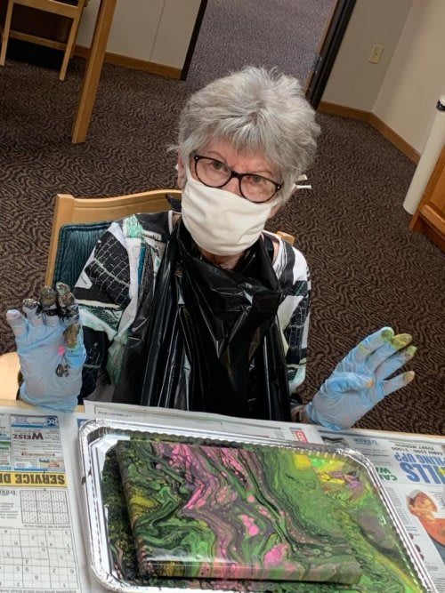 A person engaged in creating abstract art while wearing a mask and gloves.