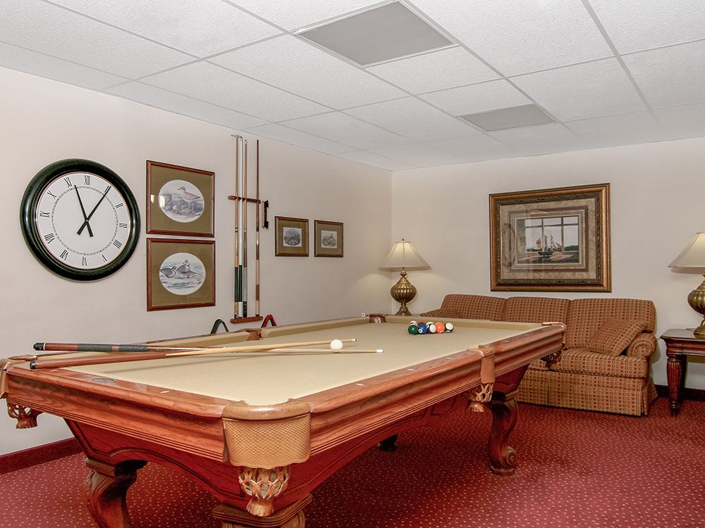 A cozy game room featuring a pool table, wall decor, and comfortable seating.