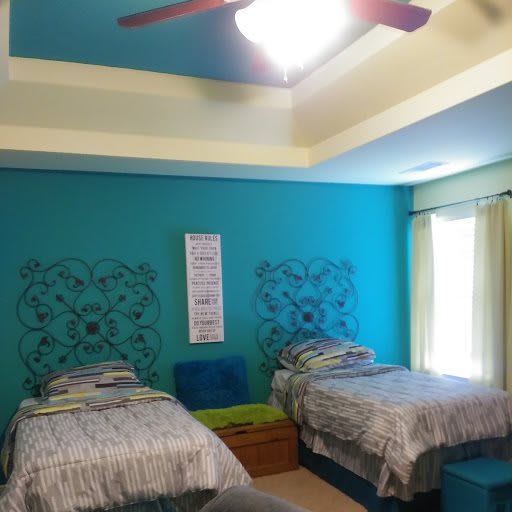 A modern bedroom featuring twin beds with blue accent walls and decorative elements.