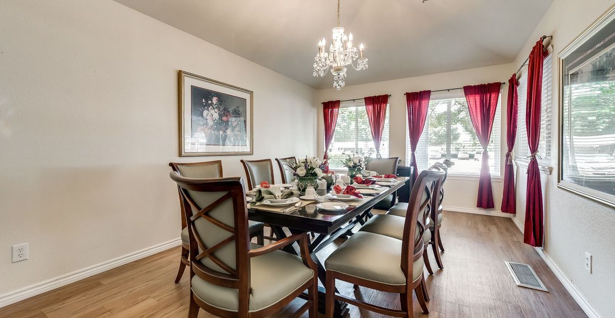 A beautifully set dining room with a large table, elegant chairs, and a chandelier.