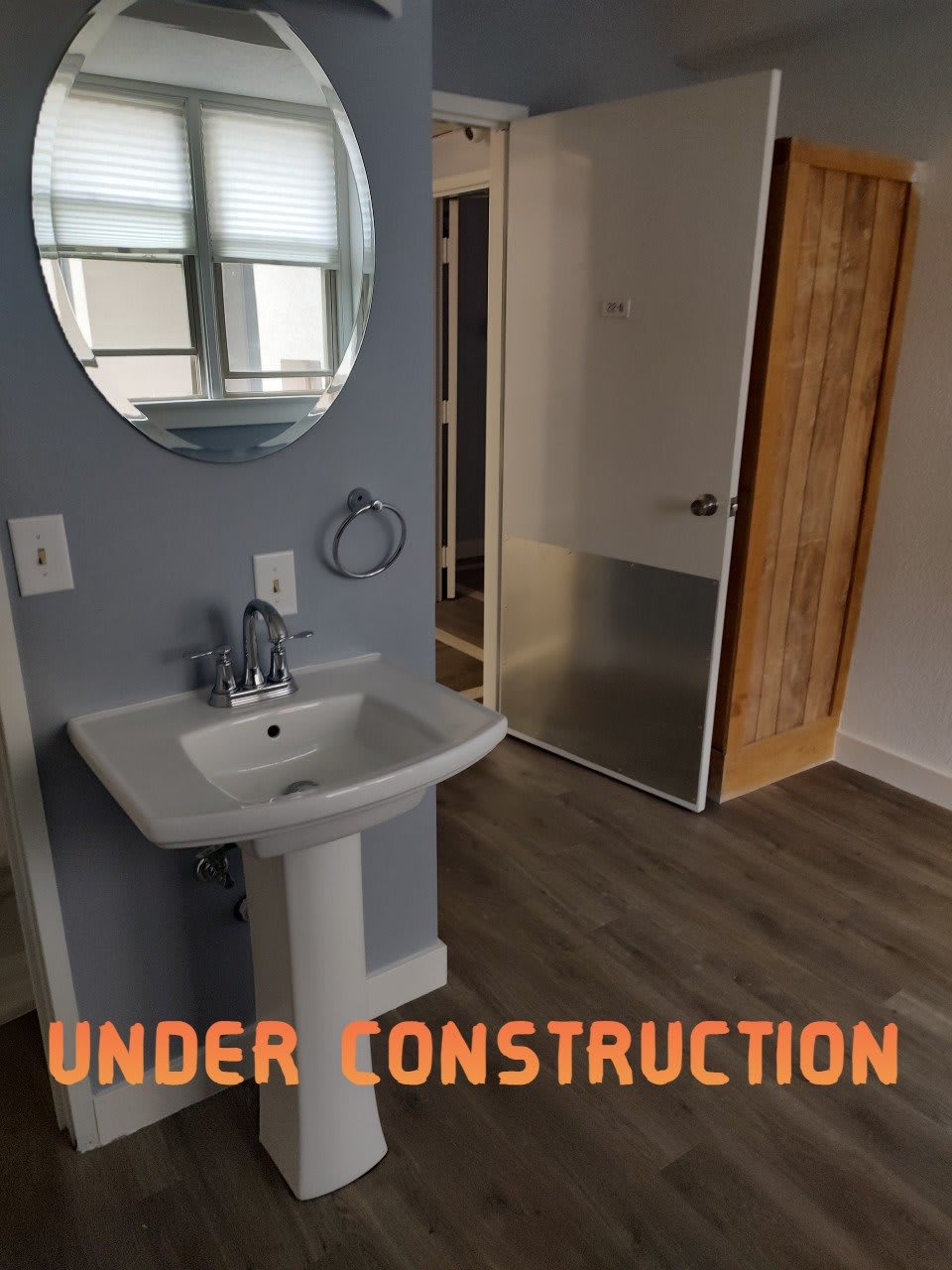 A bathroom under construction with a pedestal sink and large mirror.