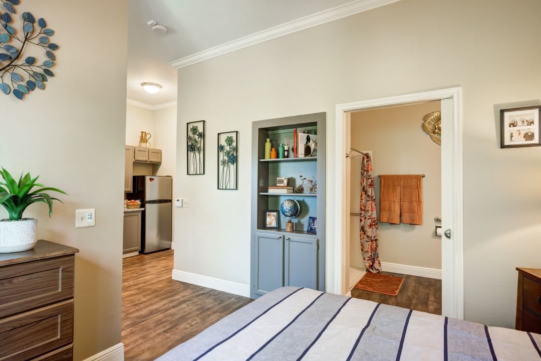A cozy room featuring a bed, kitchenette, and adjacent bathroom with tasteful decor.