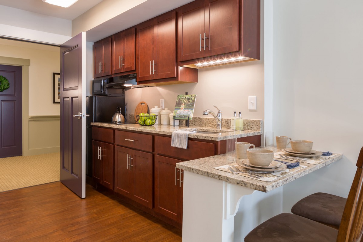 A modern kitchen with wood cabinets and a cozy dining area.