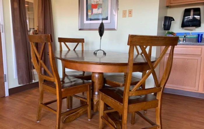 A wooden dining set with a round table and four chairs in an elegantly designed room.