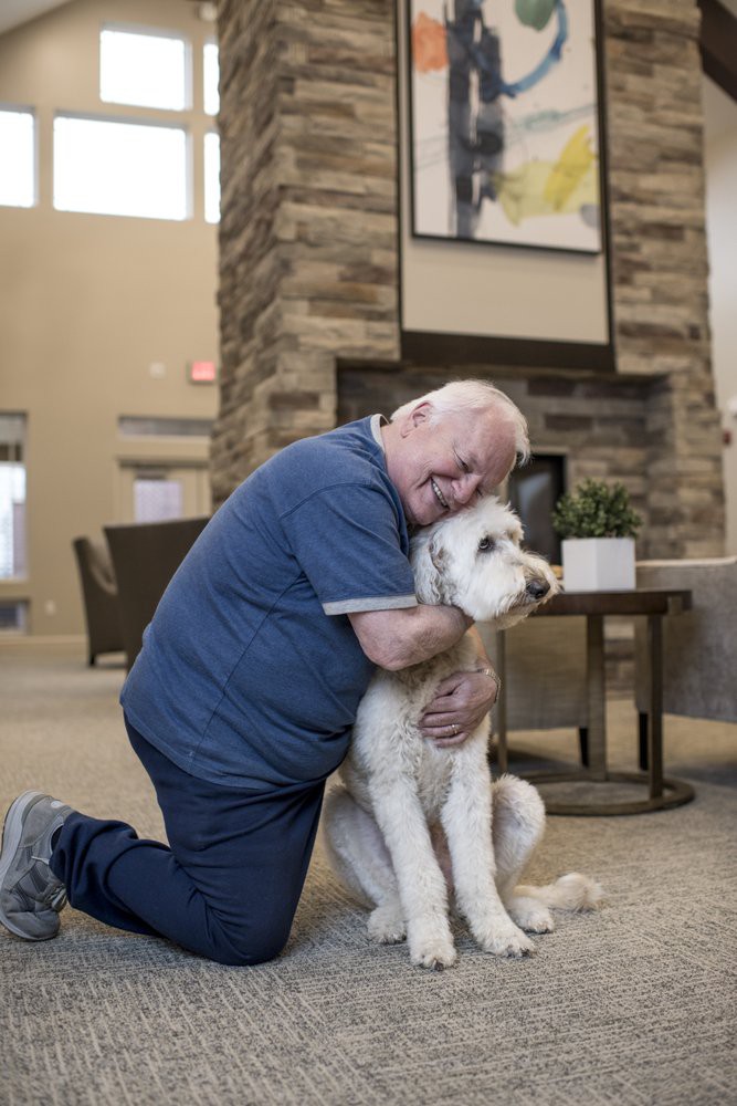 A man lovingly hugs his dog in a cozy living room setting.