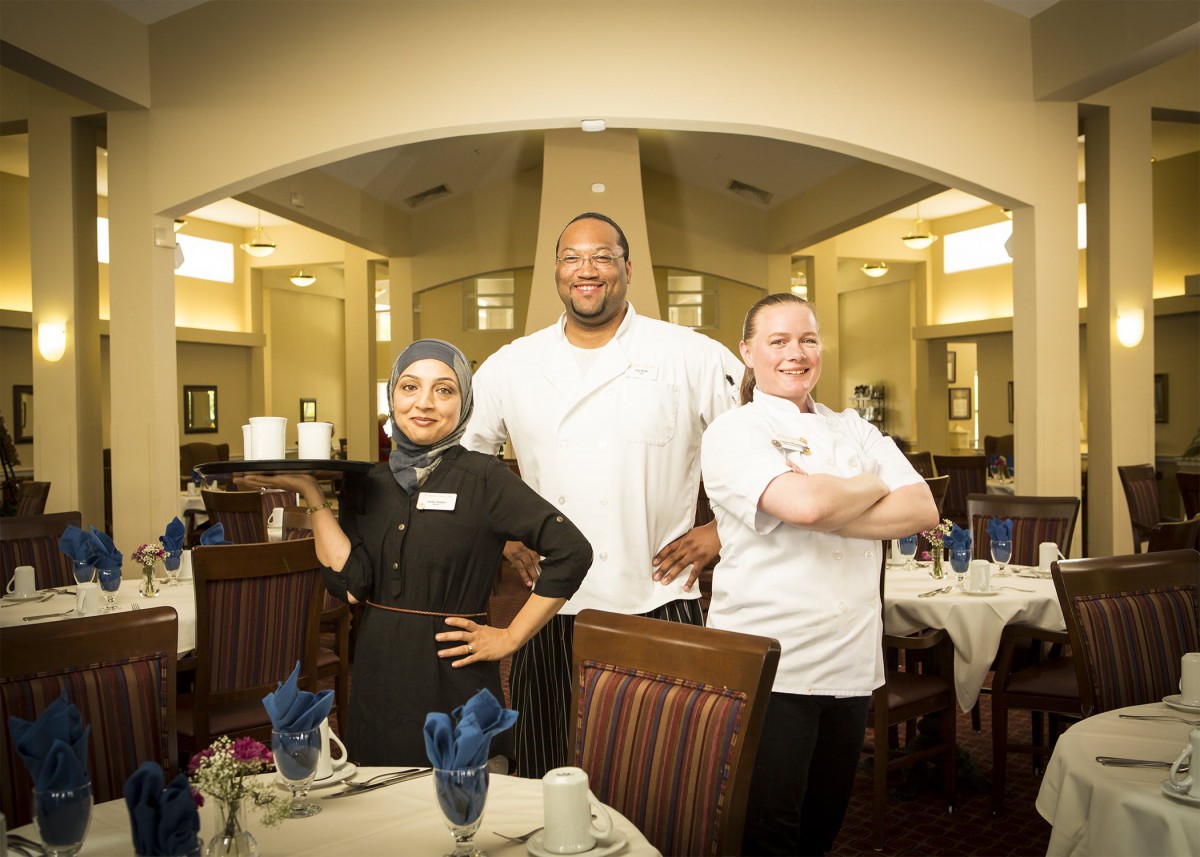 A team of chefs standing proudly in a restaurant dining area.