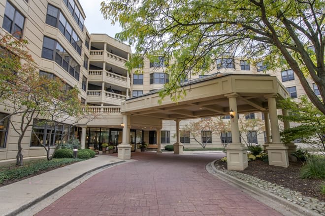 A view of a building entrance with a covered driveway surrounded by trees.