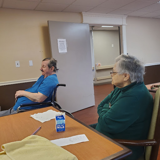 Two elderly individuals seated in a common area, engaging in quiet observation.