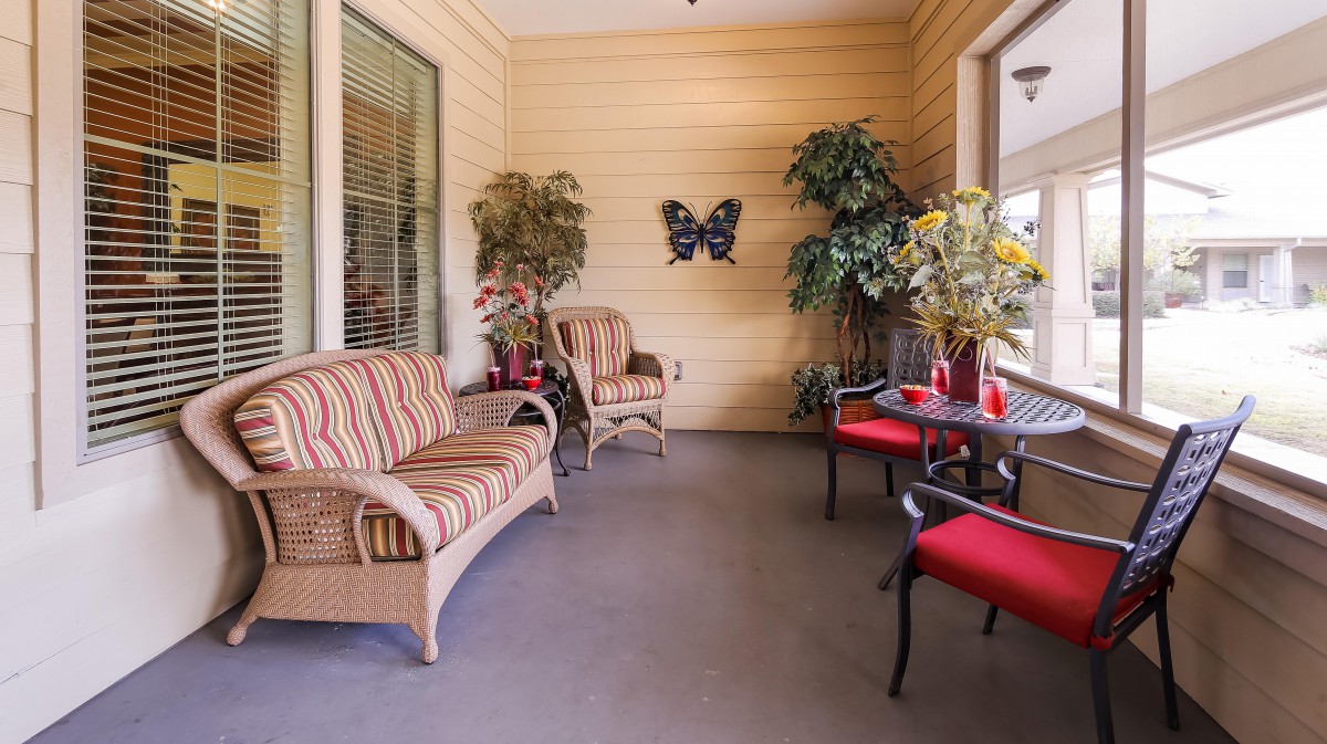A cozy porch with wicker furniture and vibrant plants creating a welcoming outdoor space.