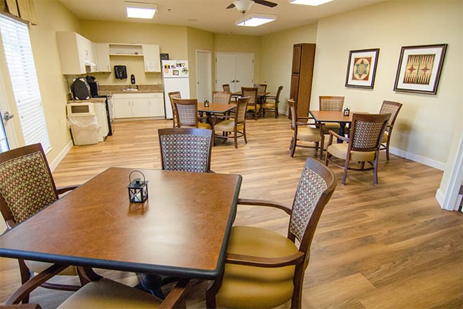 A cozy dining area with several tables and chairs, adjacent to a kitchen space.