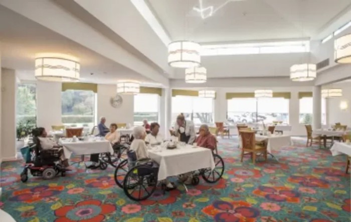 Seniors socializing in a nursing home dining room.