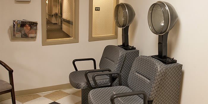 An interior view of a hair salon featuring vintage-style hair dryer chairs in the waiting area.
