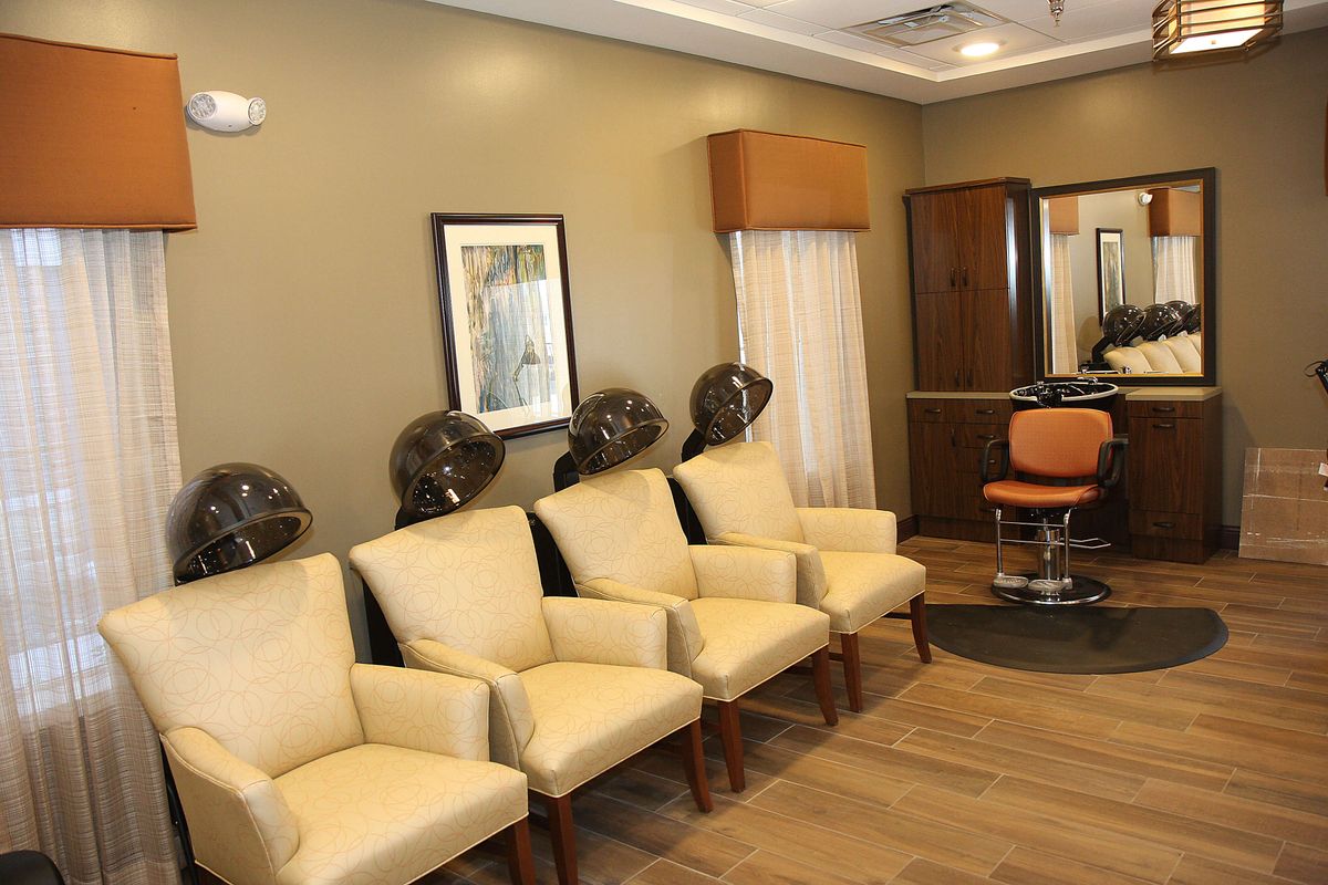 Interior of a salon with chairs and hair dryers in the waiting area.