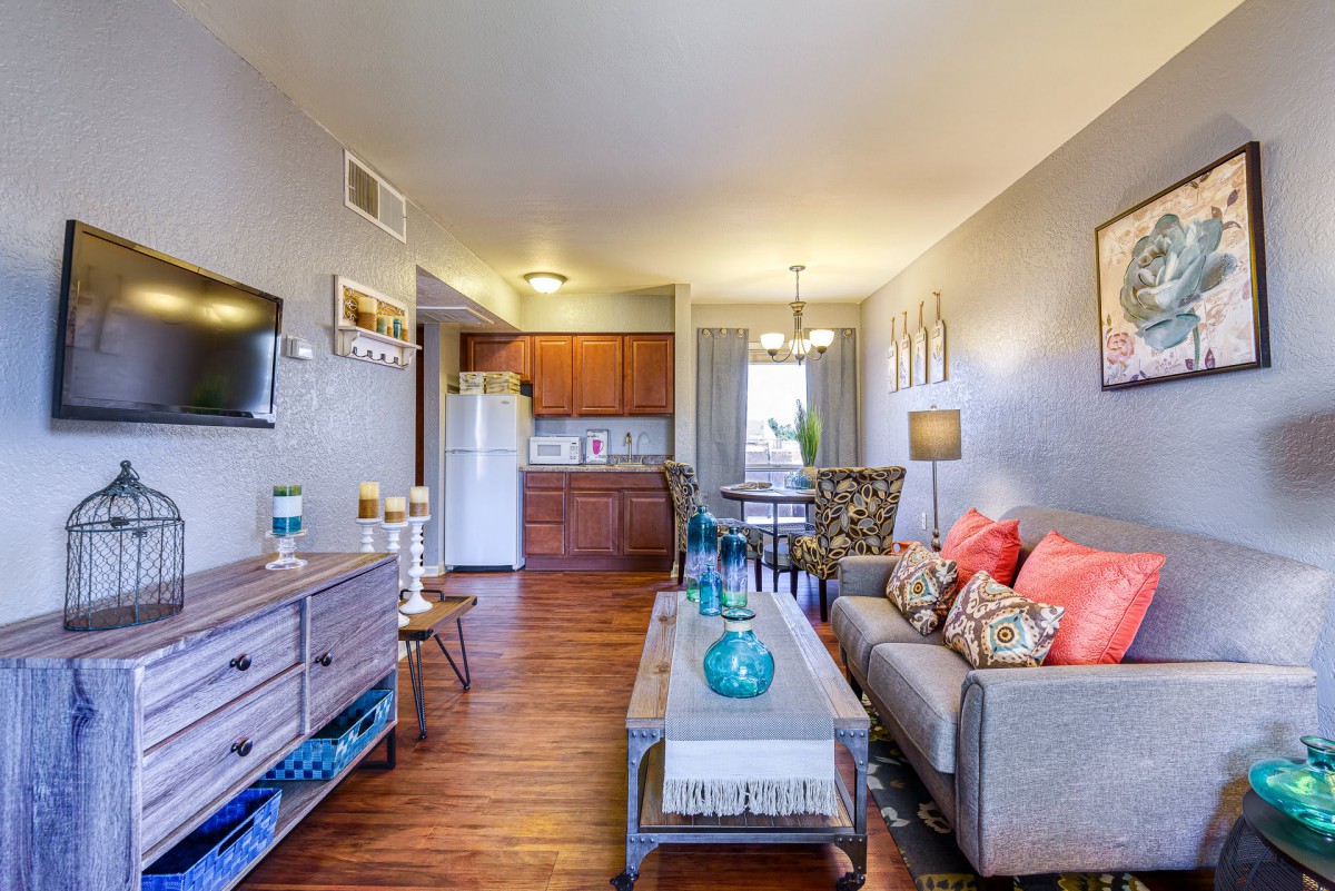 A cozy apartment living room with stylish furniture and a view into the kitchen area.