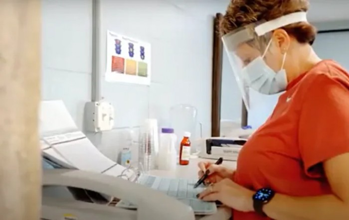 A scientist wearing PPE works with laboratory equipment.