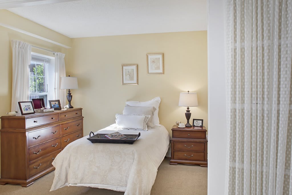 A cozy bedroom with a single bed, wooden furniture, and soft lighting.