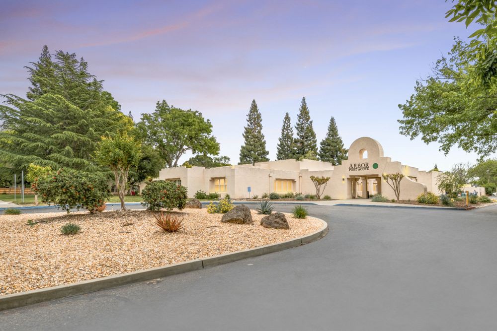 A spacious home with a wide driveway, surrounded by well-maintained landscaping and trees.