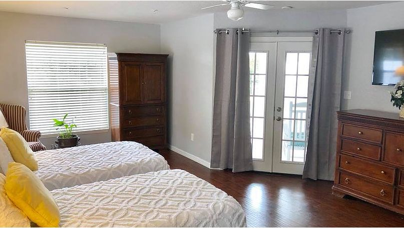 A cozy bedroom with two beds, a wooden wardrobe, and French doors leading to a balcony.