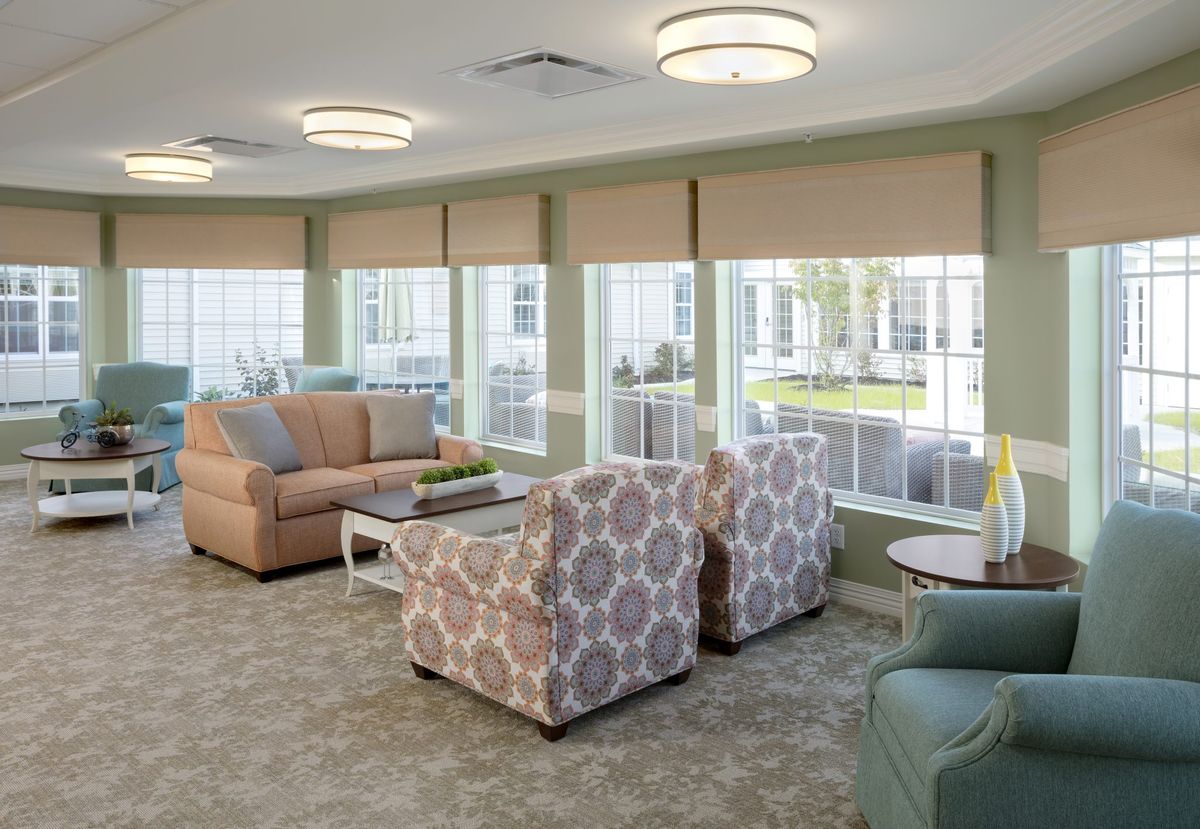 A cozy living room with sofas, patterned armchairs, and large windows providing ample natural light.