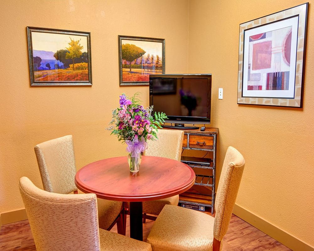 A cozy meeting room with a round table, four chairs, and decorative artwork on the walls.